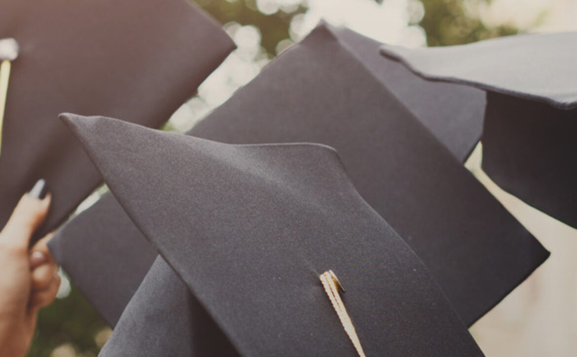 A group of graduates throwing graduation caps in the air